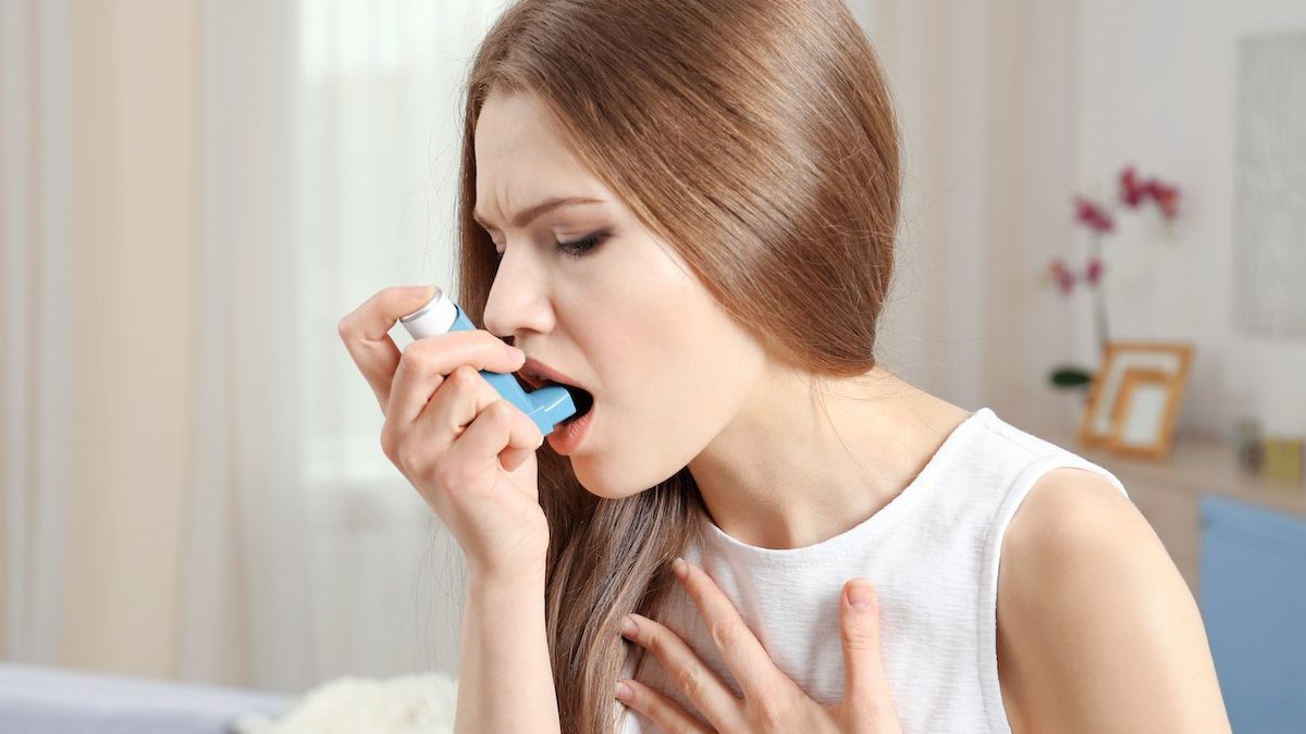 Jeune femme souffrant d'asthme et utilisant un inhalateur