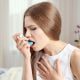 Jeune femme souffrant d'asthme et utilisant un inhalateur